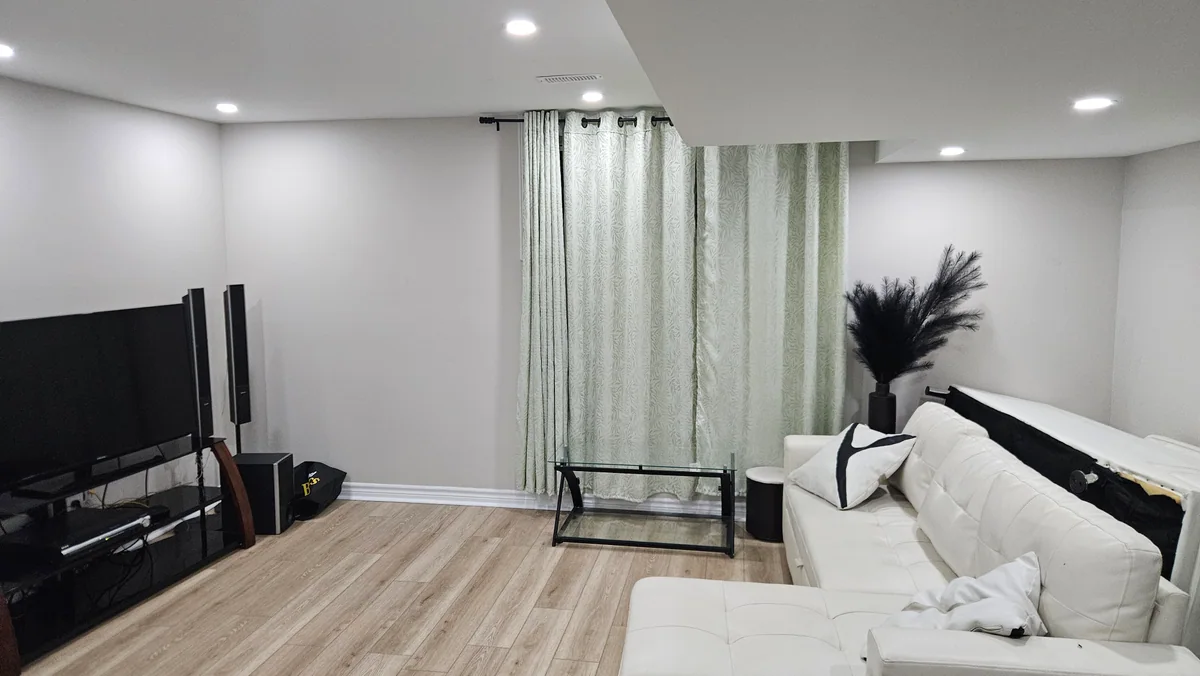 Finished basement seating area with black accent railing and recessed lighting