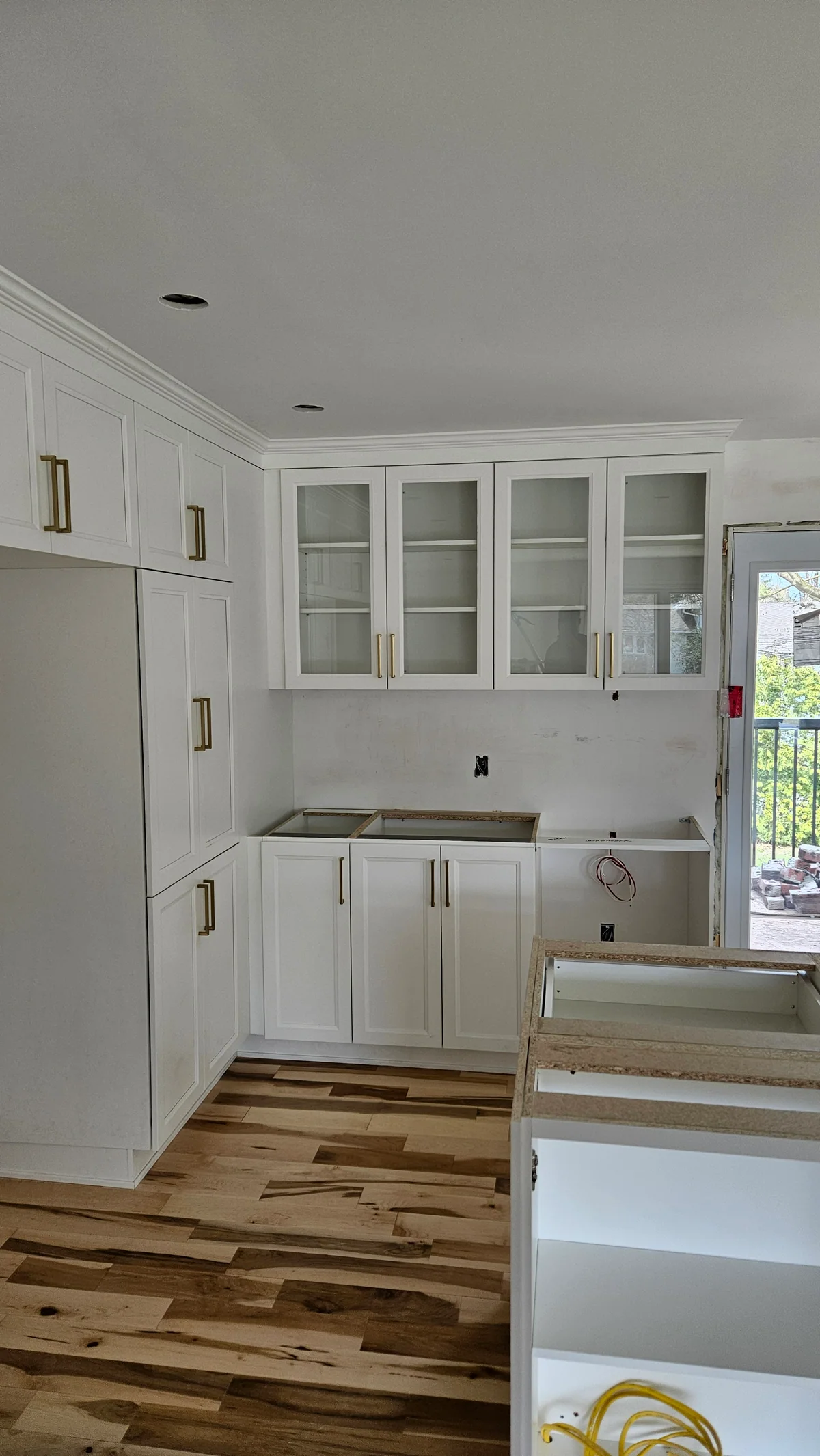 White custom kitchen cabinetry with glass-front upper cabinets and wood flooring