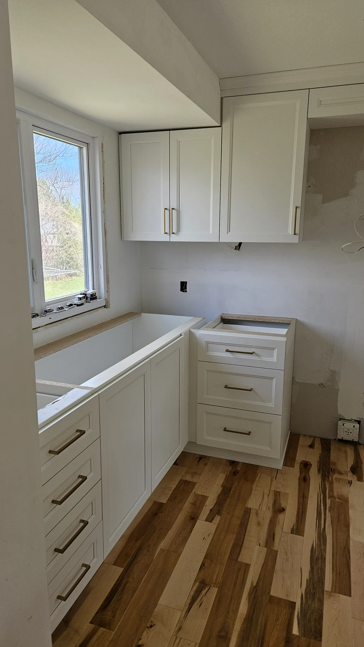 White built-in desk and drawer cabinetry installed beneath a window