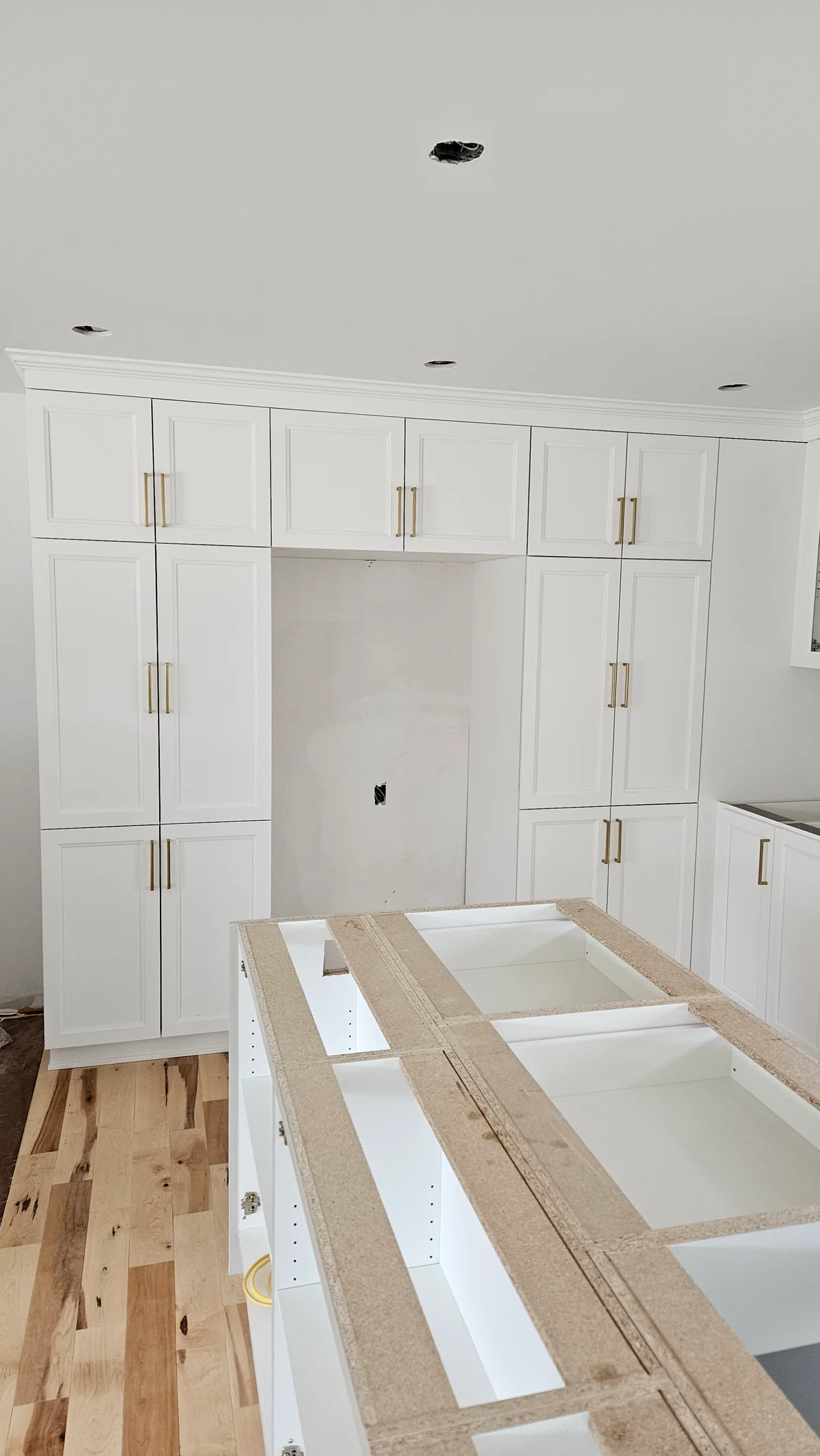 Wall of white built-in cabinets framing a central opening during installation
