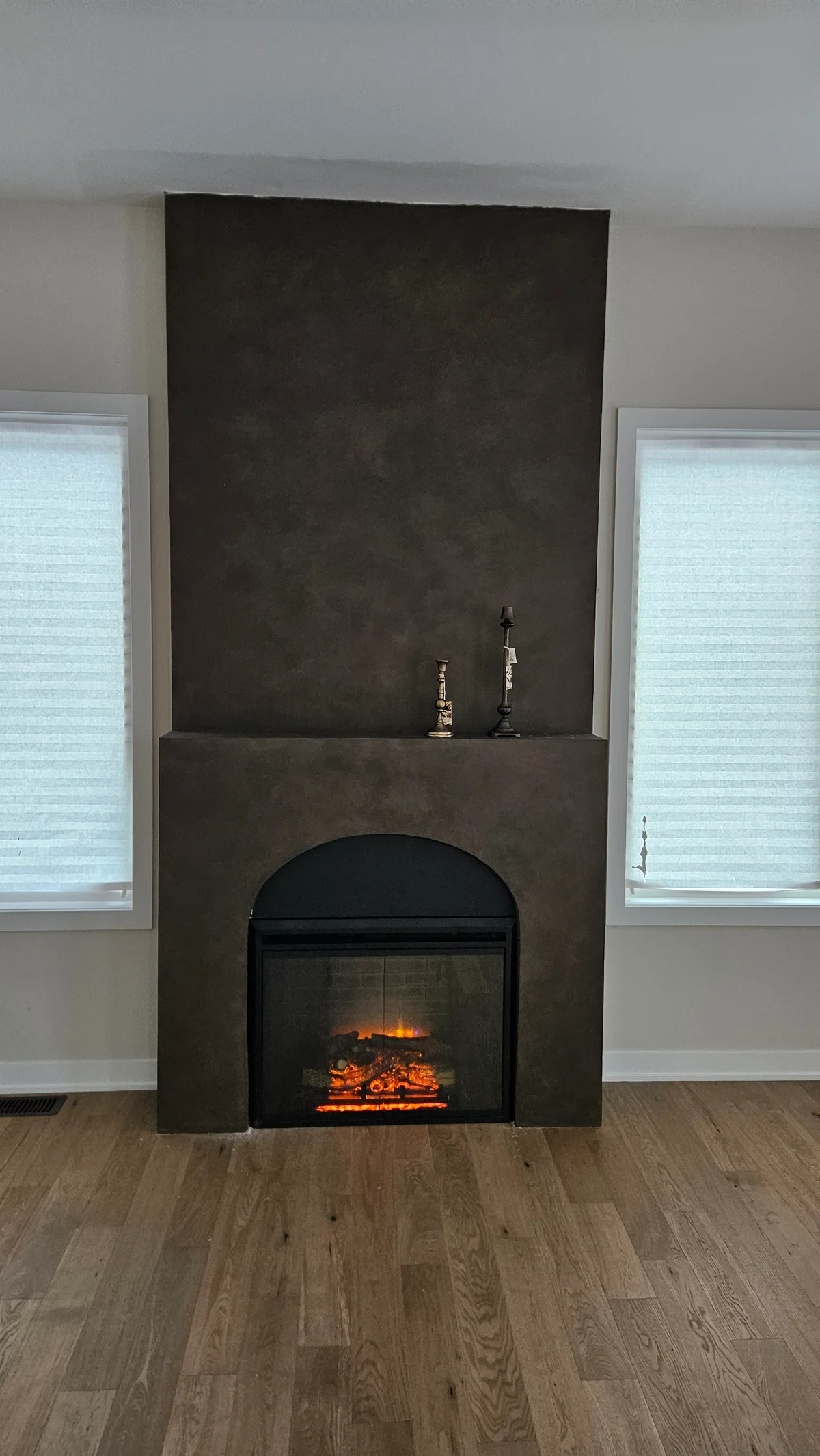 Finished dark floor-to-ceiling fireplace surround centred between two windows